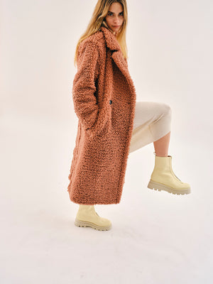 Woman wearing Bogota cream vegan boots styled with long coat and neutral outfit in side pose highlighting chunky sole