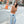 Woman wearing Cali vegan sandals in gravel blue styled with jeans and sweater posing in urban street setting