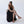 Woman wearing Camila Plus vegan lace up heels with brown ribbons styled with black dress sitting on chair in minimal studio setting