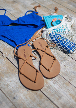 Cancun brown vegan lace-up ribbon travel sandals flat lay with beach essentials