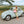 Woman wearing vegan lace up sandals styled with green dress standing by vintage car during summer road trip in Europe