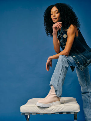 Woman wearing vegan platform boots styled with denim outfit with one foot elevated highlighting chunky sole and design