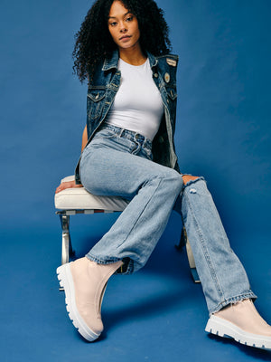 Woman wearing vegan platform boots styled with denim outfit sitting in studio highlighting chunky sole and fit