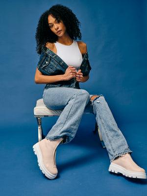 Woman wearing vegan platform boots styled with denim outfit sitting in studio, casual sustainable fashion look