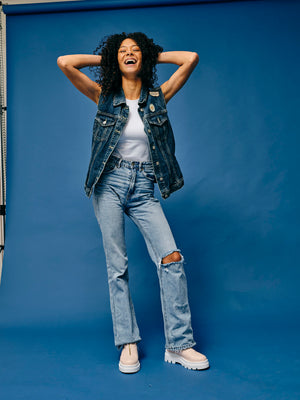 Woman wearing vegan platform boots styled with denim outfit in studio smiling and posing, casual sustainable fashion