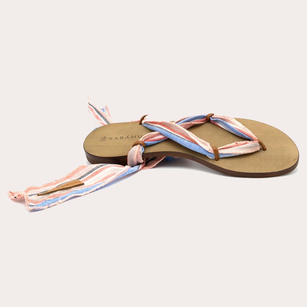 A pair of sandals with pastel striped ribbons in pink, blue, and beige tones for a playful look.