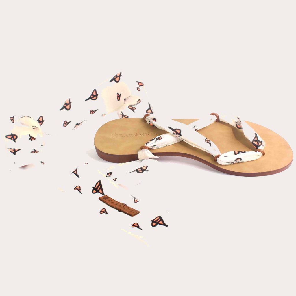 Sandals with butterfly-patterned ribbons surrounded by small paper butterflies on a light background.