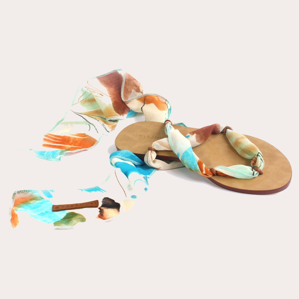 A tropical-inspired pair of sandals featuring colorful ribbons with shades of turquoise, orange, and green.