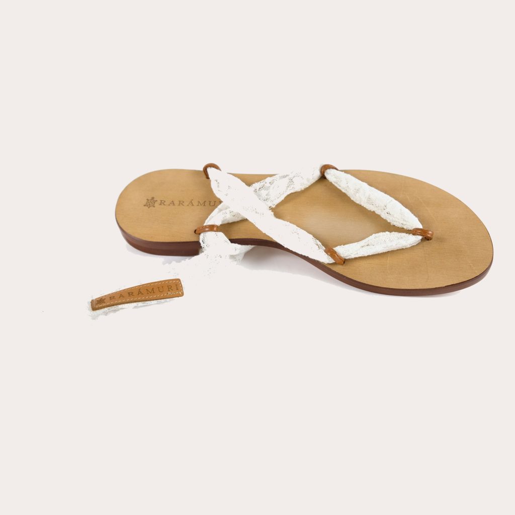 A pair of Rarámuri sandals with soft white ribbons tied elegantly around the cork base.